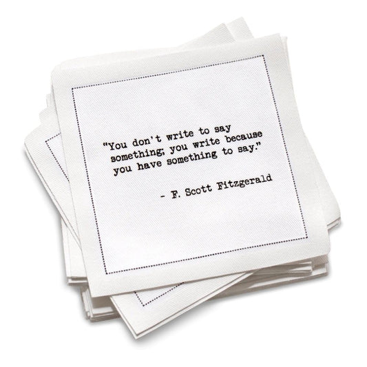 Stack of white cotton cocktail napkins with black text quote by F. Scott Fitzgerald on a white background