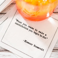 Organic cotton cocktail napkin with printed quote 'When you cease to make a contribution you begin to die.'